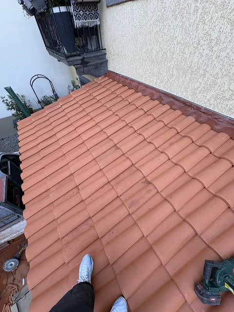 Tuiles terre cuite posées sur un pan de toiture attenant à une façade