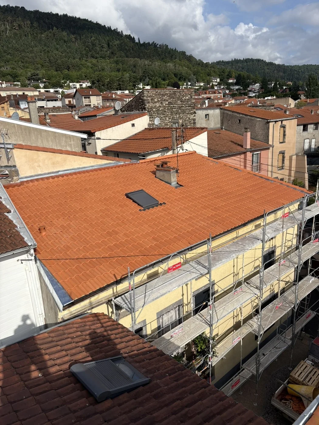 Vue d’ensemble d’une couverture en tuiles terre cuite avec une fenêtre de toit
