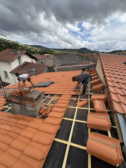 Équipe au travail sur une couverture, entre zones de liteaux et tuiles déjà posées